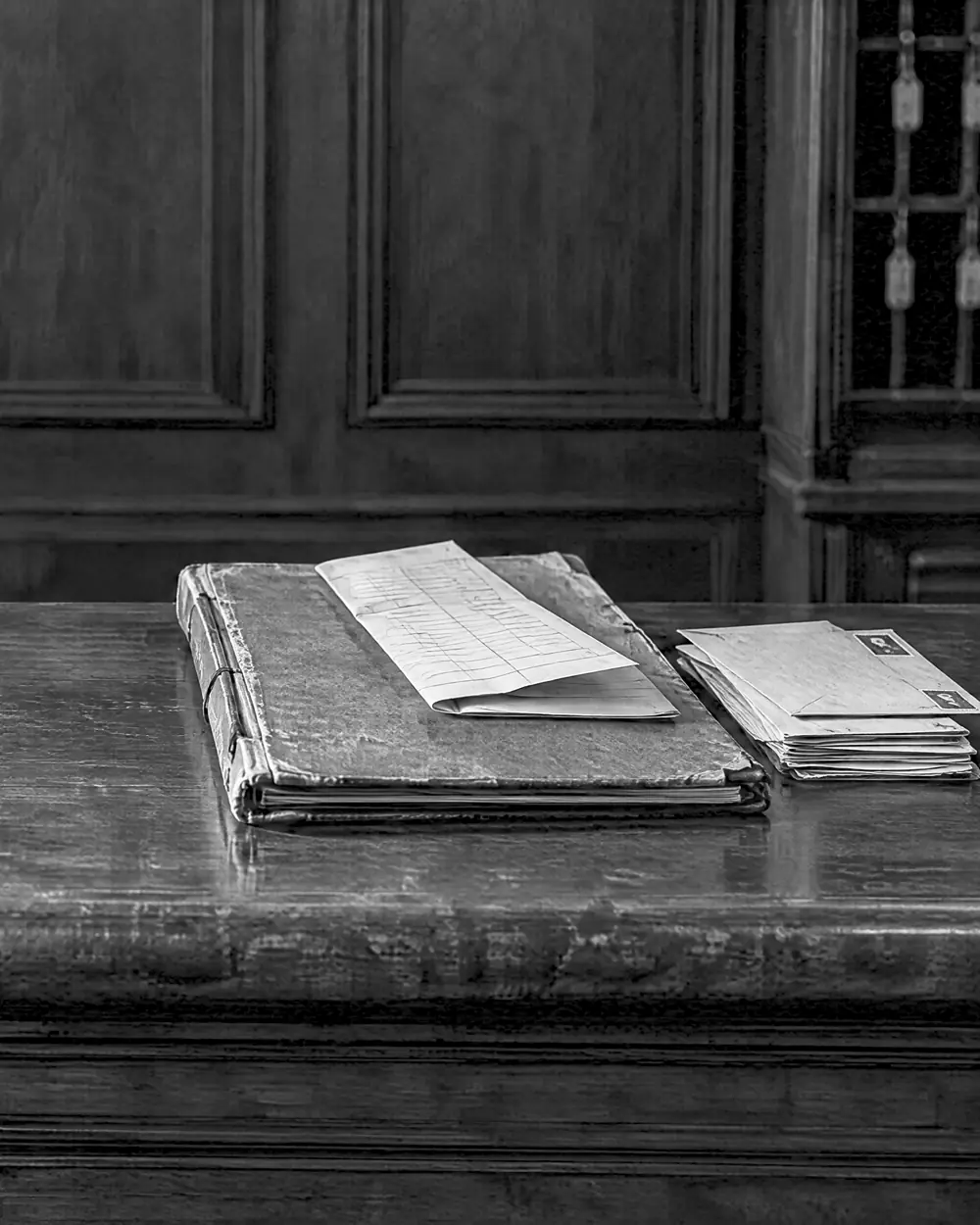 Registerbuch mit gefalteter Zimmerliste und Poststapel daneben auf dem Rezeptionstresen